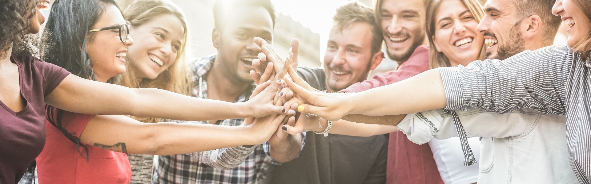 Young happy people stacking hands outdoor